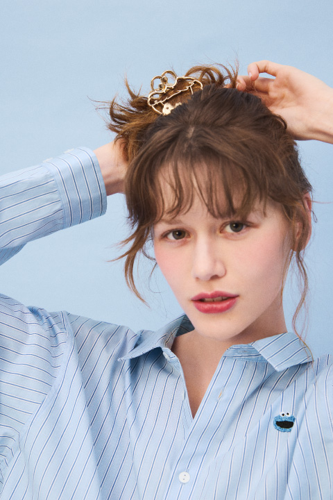 ブルーのシャツとネイビーのパンツとベージュのソックスとブラックのブーツを着用した女性